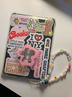 a pink pacifier and beaded bracelet sitting on top of a white table next to a book