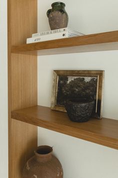 two wooden shelves with vases and books on them