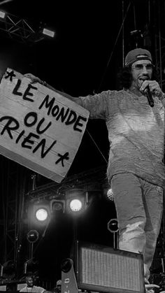 a man standing on top of a stage holding a sign that says je monde ou rien