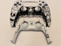 two video game controllers sitting next to each other on a white surface with black and white designs