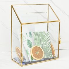 a glass box filled with orange slices and other items on top of a table next to a marble wall