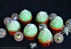 cupcakes with green frosting and spooky eyes are arranged on a table