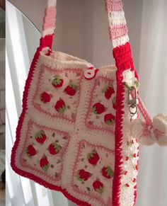 a crocheted purse hanging from the side of a wall next to a mirror