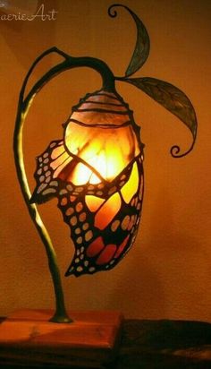 a lamp with a butterfly on it sitting on a table next to a bookcase