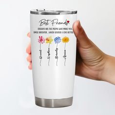 a person holding a white coffee cup with colorful flowers on the bottom and saying best friends