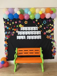 an orange bench in front of a black wall with balloons