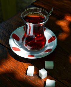 a glass cup filled with liquid sitting on top of a saucer next to cubes of sugar