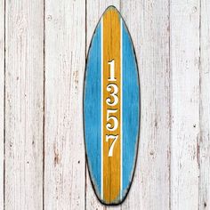 a wooden surfboard with the number seventy seven on it's side against a white fence