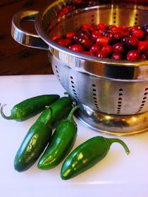 some red and green peppers in a colander on a white counter with other vegetables