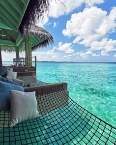 a hammock on the beach with blue water and white clouds in the background