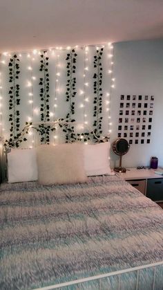 a bed that has some lights on the headboard and pillows in front of it