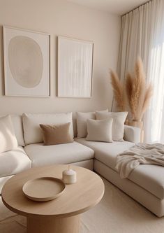 a living room filled with white furniture and large pictures hanging on the wall above it