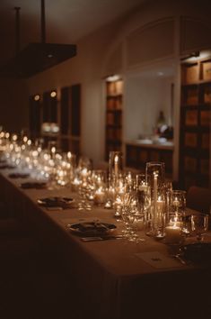 a long table with many glasses on it and candles lit up in front of them