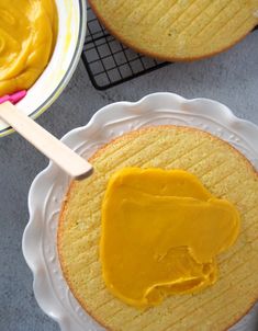 two cakes with yellow icing sitting on top of each other