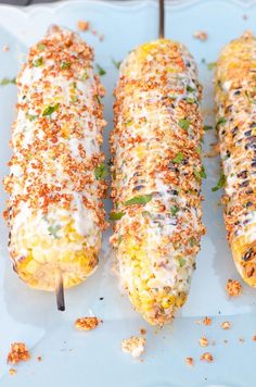 three corn on the cob covered in cheese and seasoning