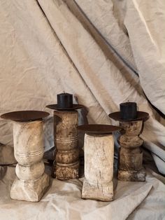 four wooden vases sitting next to each other on a white cloth covered tablecloth