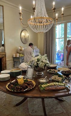 a dining room table with food on it and people standing around the table in the background