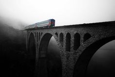 a train is crossing over a bridge in the fog