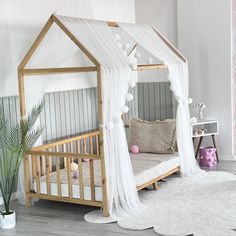 a white canopy bed with sheer curtains on the top and bottom, in a child's room