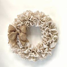 a burlocked wreath with a bow on the front is hanging against a white wall