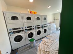 several washers and dryers are lined up in the laundry room