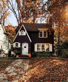 a black house with white trim surrounded by fall leaves