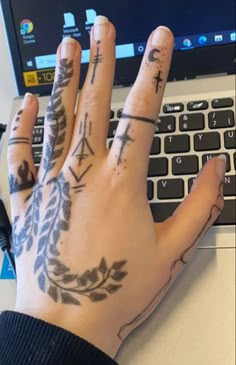 a person's hand with tattoos on it next to a laptop computer and keyboard