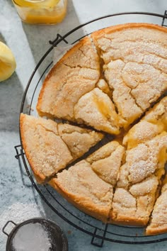 a close up of a cake on a cooling rack with slices cut out and lemons in the background