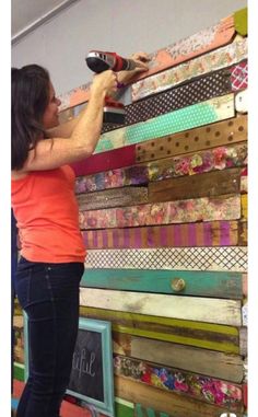 a woman standing next to a wall made out of different colored strips of paper and scissors