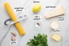 ingredients to make pasta laid out on a white counter top with lemons, parmesan cheese, parsley and butter