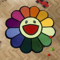 a multicolored rug with a smiling face on the floor next to toy cars