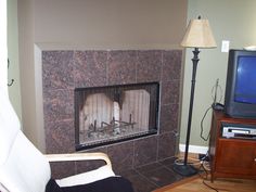 a fireplace in a living room with a television on the wall and a lamp next to it