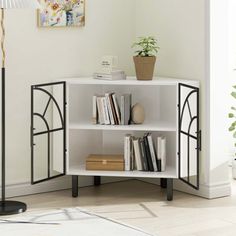 a white book shelf with books on it in a living room next to a lamp