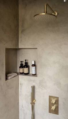 a bathroom with a gold faucet, shower head and soap dispenser