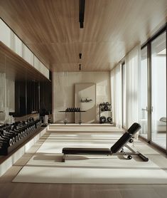 there is a gym with rows of exercise equipment on the floor and in front of large windows