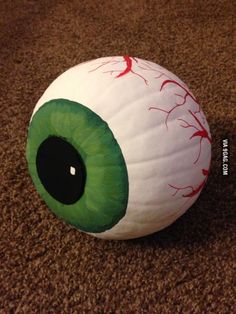 an eyeball on the ground with red paint all over it's face and green eyes