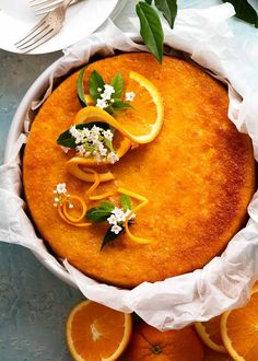 a cake with orange slices and flowers on top is surrounded by other food items, such as utensils