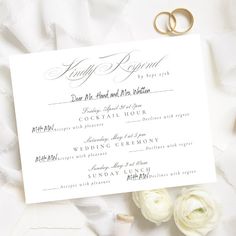 two wedding rings are laying on top of a white paper with the names of their guests