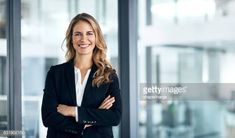 a business woman standing in an office building with her arms crossed and smiling at the camera