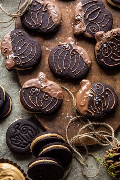 cookies with chocolate frosting and decorated pumpkins are on a wooden board next to pine cones