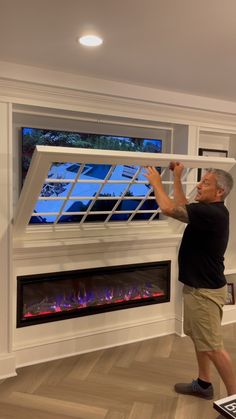 a man standing in front of a fireplace with an electric fire place on the wall