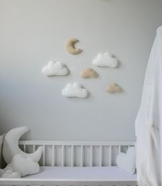 there is a crib in the room with clouds on the wall and a stuffed animal next to it