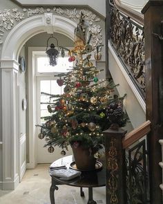 a decorated christmas tree sitting on top of a table next to a bannister