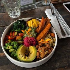 a bowl filled with lots of different types of food on top of a wooden table