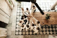 a group of men standing in a circle on top of a tiled floor next to a wooden table