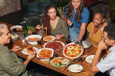 a group of people sitting around a table eating pizza