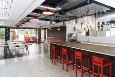 an open kitchen and dining area with red bar stools in front of the counter