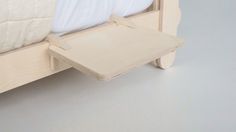 a wooden bed frame with white sheets on it