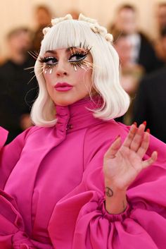 lady with white hair and black eyeliners posing for the camera in front of a crowd