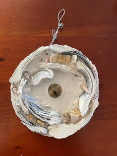 a bowl made out of clay and rocks on top of a wooden table with a chain hanging from it